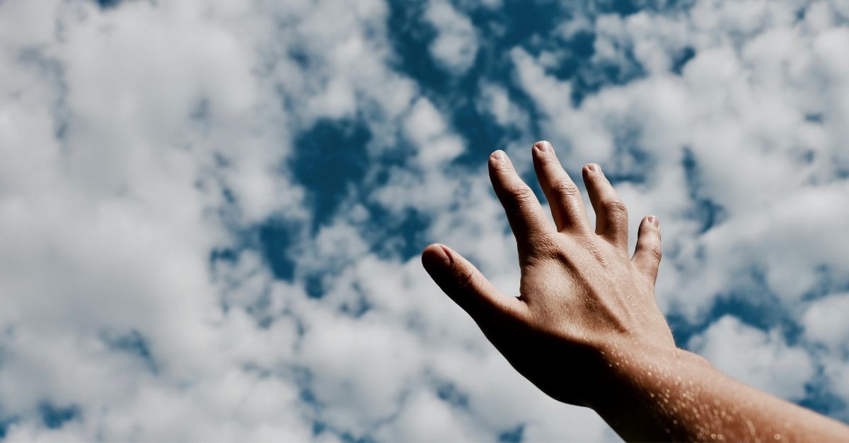 Hand raised in prayer towards the sky; why do Christians pray?